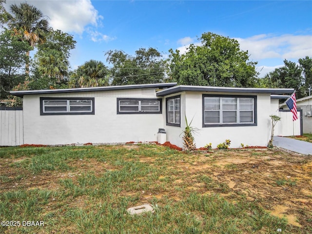 ranch-style home with fence, a front lawn, and stucco siding