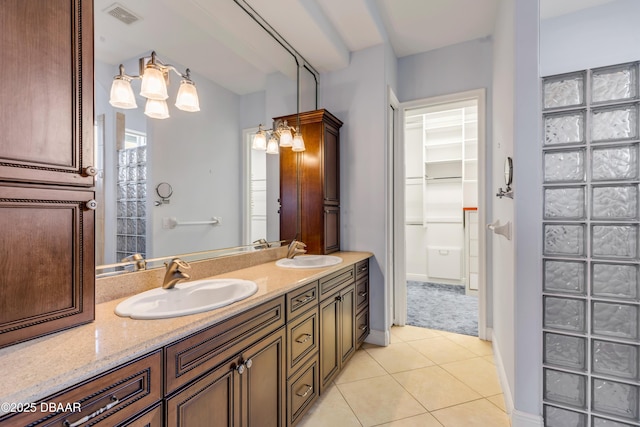 bathroom featuring visible vents, a walk in closet, a sink, and tile patterned floors