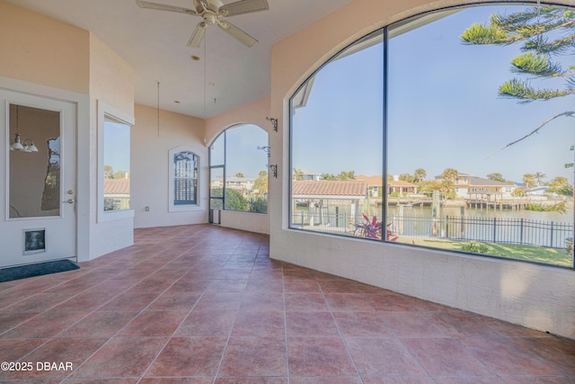 unfurnished sunroom featuring a ceiling fan and a water view