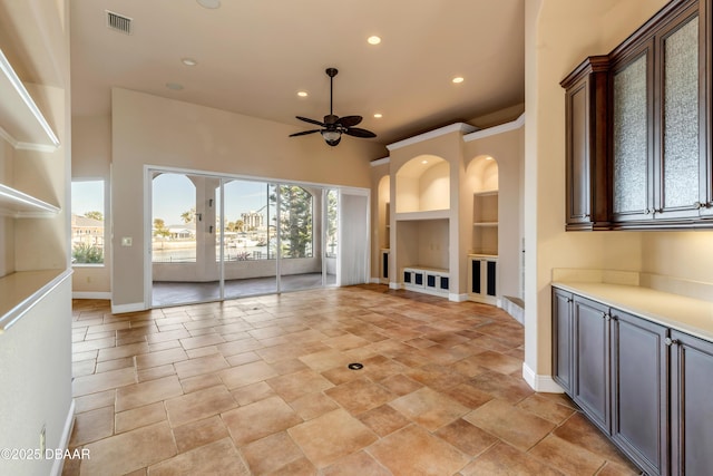 unfurnished living room with baseboards, built in shelves, visible vents, and a wealth of natural light