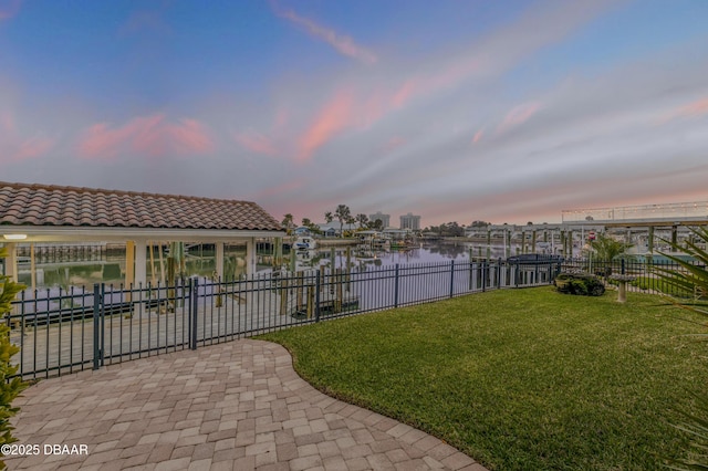 exterior space featuring a yard, a dock, a water view, and fence