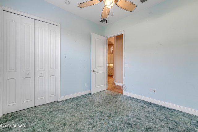 unfurnished bedroom featuring carpet, arched walkways, a closet, ceiling fan, and baseboards