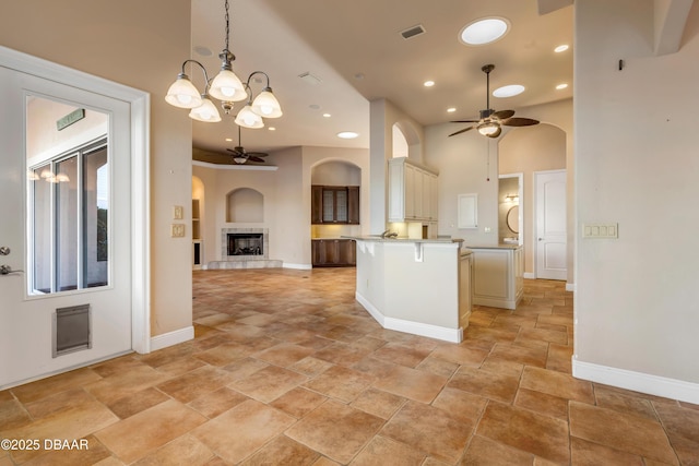 kitchen with ceiling fan with notable chandelier, a peninsula, open floor plan, and visible vents