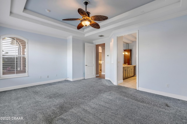 unfurnished bedroom featuring ornamental molding, a raised ceiling, light colored carpet, and baseboards