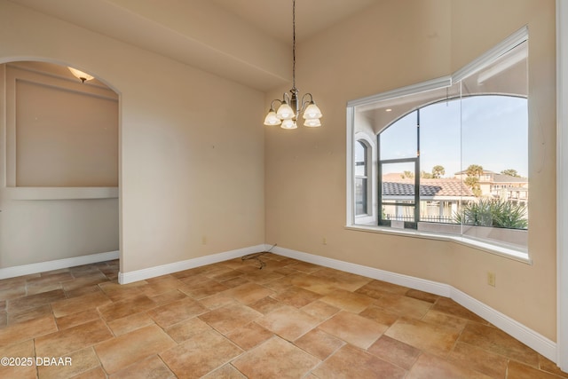 empty room featuring an inviting chandelier and baseboards