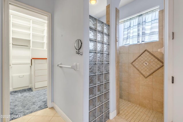 full bathroom featuring tile patterned flooring, a spacious closet, baseboards, and walk in shower