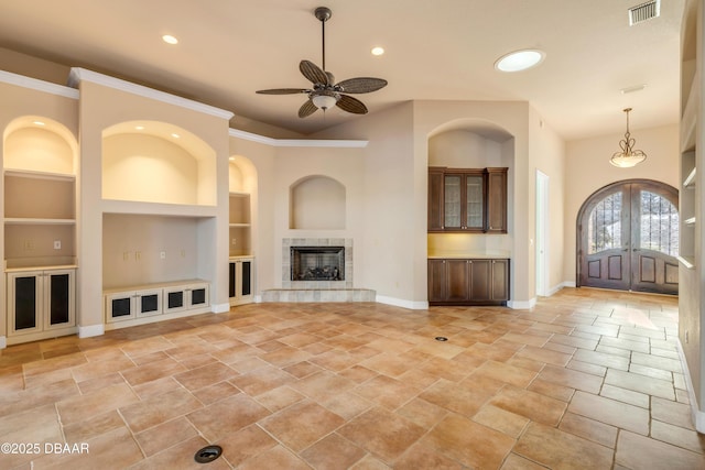 unfurnished living room with baseboards, visible vents, french doors, built in shelves, and a fireplace