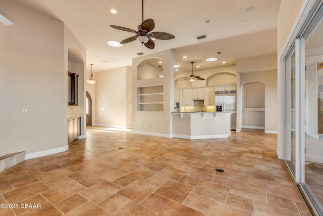 unfurnished living room featuring arched walkways, visible vents, and ceiling fan