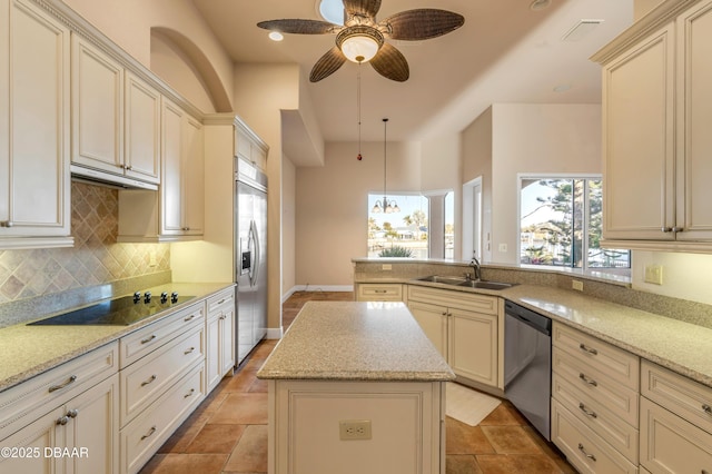 kitchen featuring tasteful backsplash, a peninsula, stainless steel appliances, cream cabinetry, and a sink