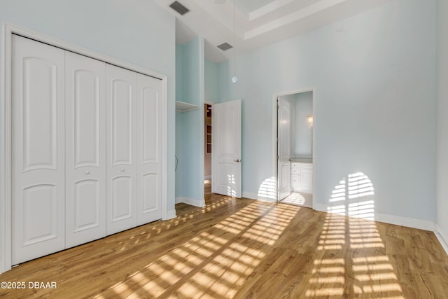 unfurnished bedroom with baseboards, a closet, visible vents, and wood finished floors