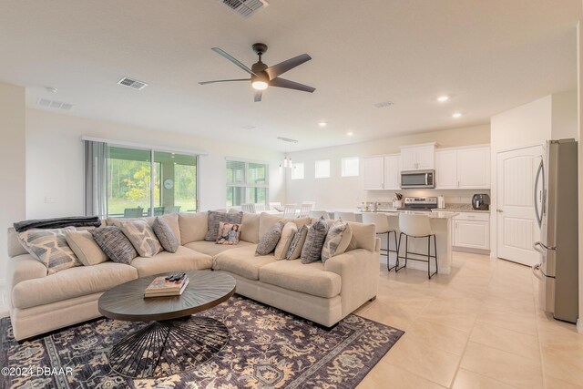 living room with a ceiling fan, healthy amount of natural light, light tile patterned floors, and recessed lighting