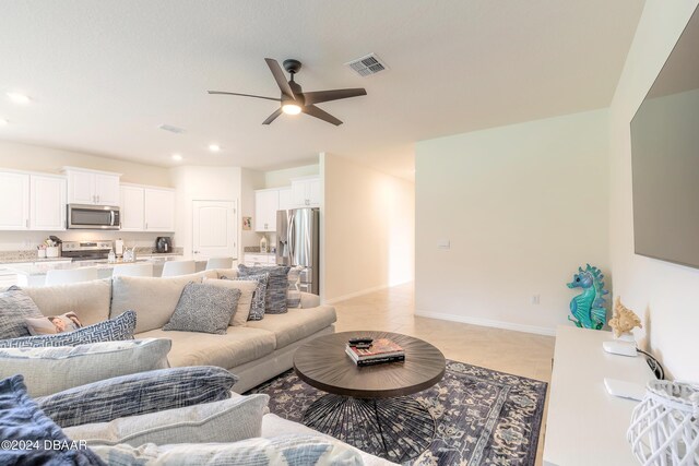 living area with a ceiling fan, recessed lighting, and baseboards