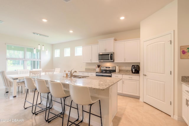 kitchen featuring stainless steel appliances, a sink, a kitchen breakfast bar, white cabinetry, and recessed lighting