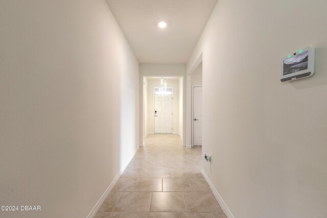 hall featuring baseboards, light tile patterned flooring, and recessed lighting