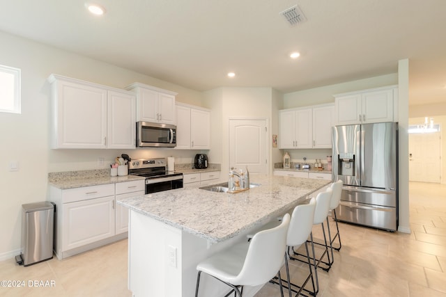 kitchen featuring sink, white cabinetry, stainless steel appliances, and a kitchen island with sink