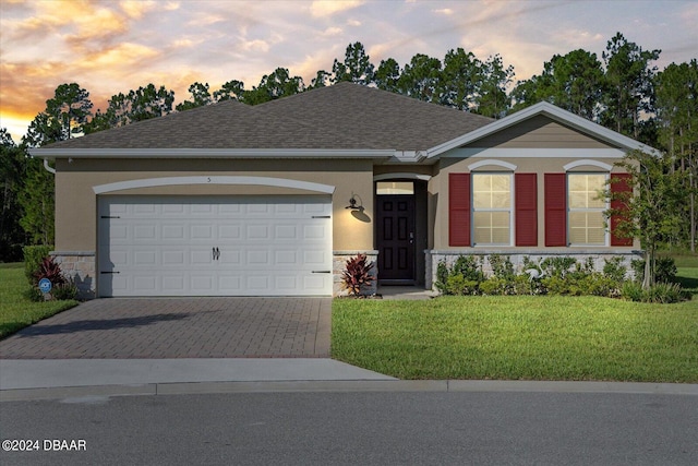 ranch-style home featuring a garage and a yard