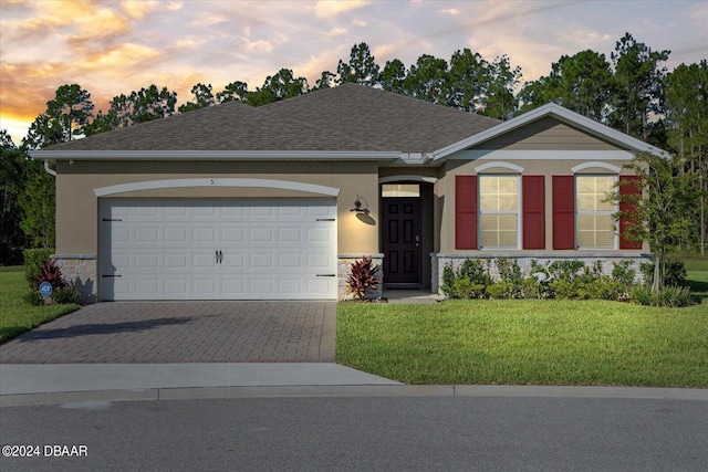 ranch-style house featuring driveway, a front lawn, stucco siding, stone siding, and a garage