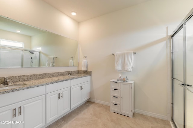 bathroom with a shower stall, double vanity, baseboards, recessed lighting, and tile patterned flooring
