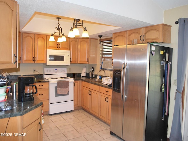 kitchen featuring dark countertops, a sink, light tile patterned flooring, white appliances, and decorative light fixtures