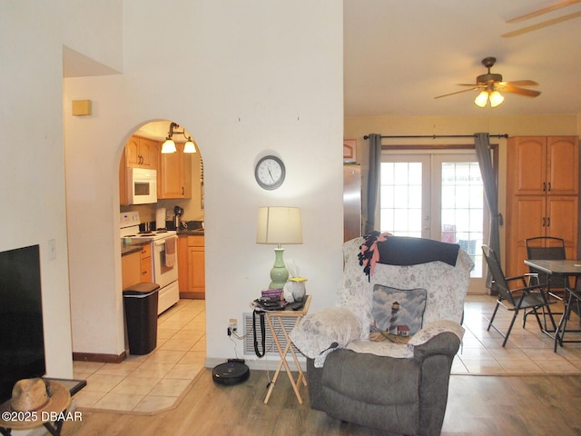 living room with arched walkways, a ceiling fan, light tile patterned floors, and french doors
