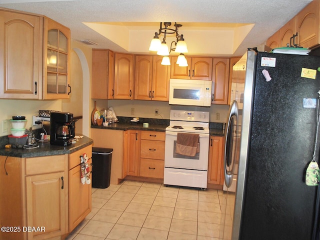 kitchen featuring dark countertops, light tile patterned flooring, white appliances, glass insert cabinets, and arched walkways