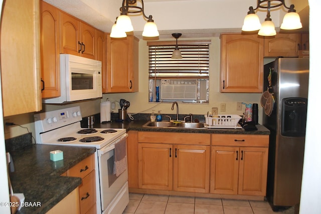 kitchen with dark countertops, a sink, white appliances, and light tile patterned floors