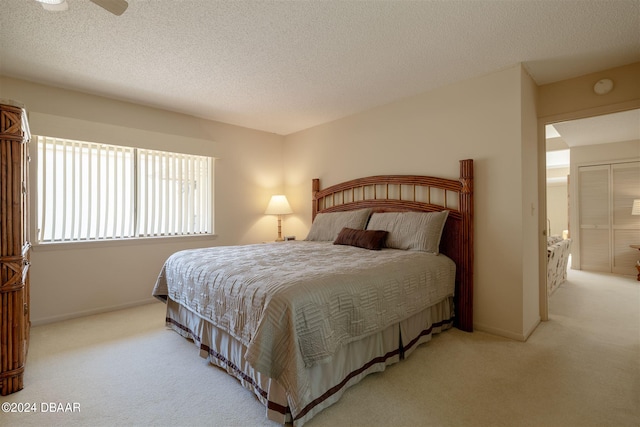 bedroom with a textured ceiling, light carpet, and ceiling fan