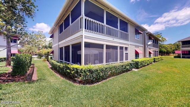 rear view of property featuring a sunroom and a yard