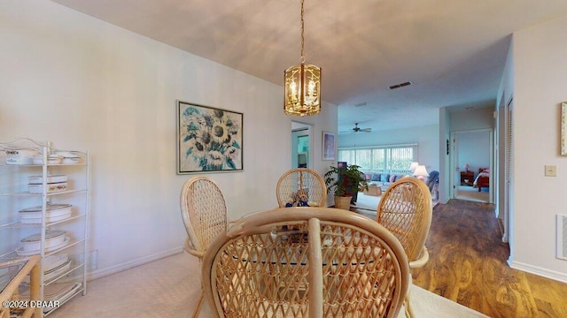 dining space featuring ceiling fan with notable chandelier and wood-type flooring