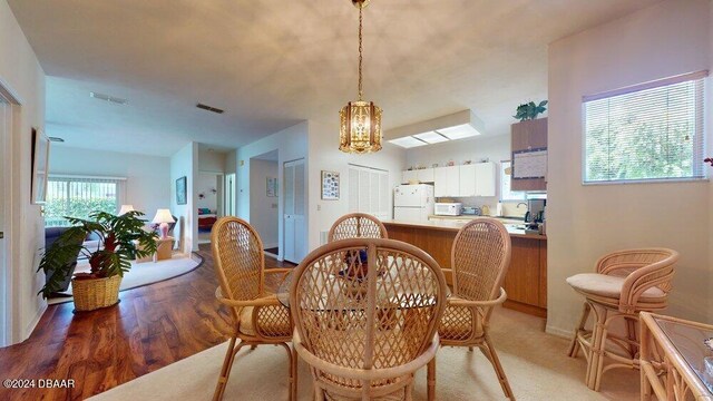 dining area with light wood-type flooring and an inviting chandelier