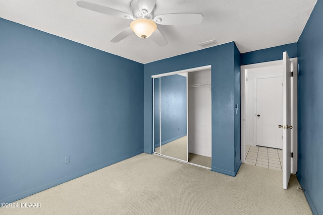 unfurnished bedroom with ceiling fan, a closet, and light carpet