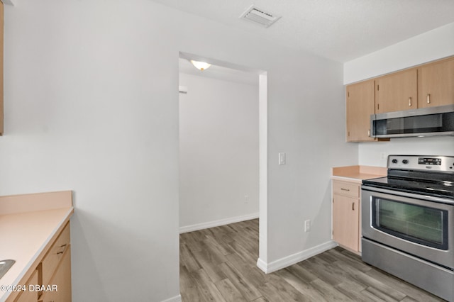 kitchen featuring light brown cabinets, light wood-type flooring, and appliances with stainless steel finishes