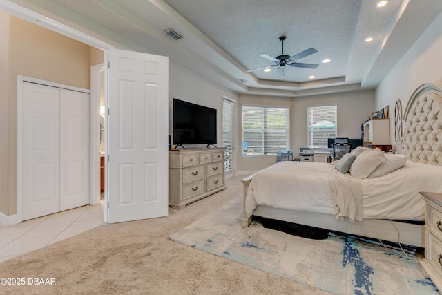 bedroom featuring light carpet, a tray ceiling, recessed lighting, a textured ceiling, and a ceiling fan