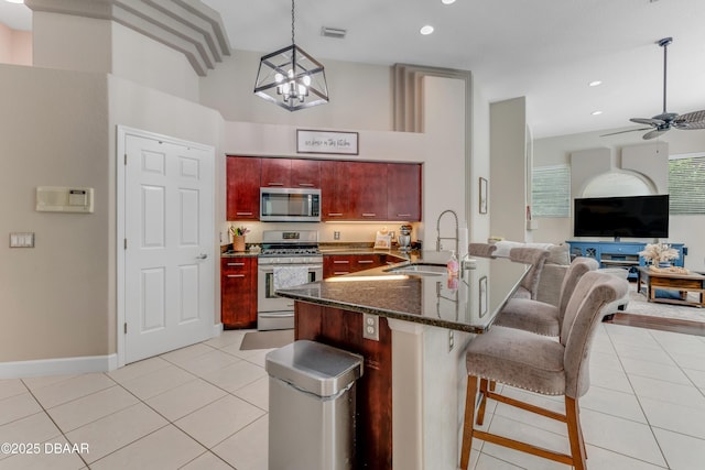 kitchen with stainless steel appliances, a sink, dark brown cabinets, light tile patterned floors, and recessed lighting