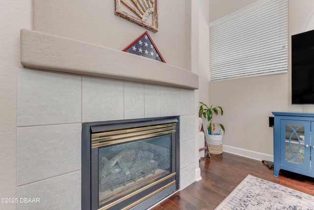detailed view of a tile fireplace, wood finished floors, and baseboards