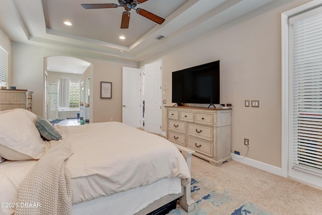 bedroom featuring arched walkways, baseboards, recessed lighting, connected bathroom, and a raised ceiling