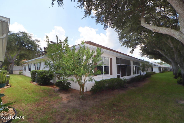 view of property exterior with a sunroom and a lawn