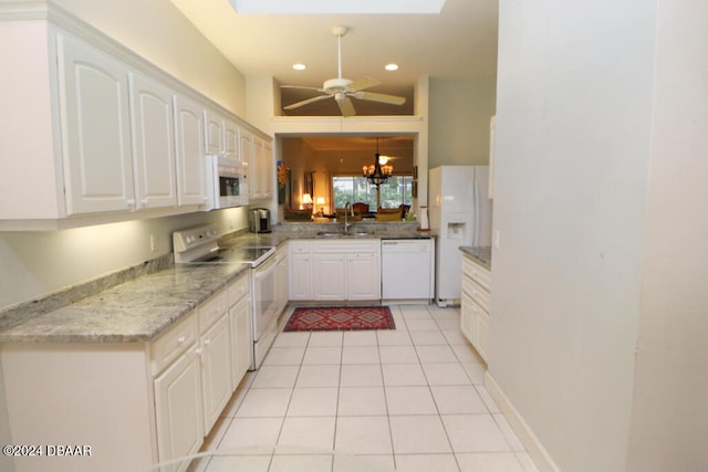 kitchen featuring white cabinets, sink, white appliances, and vaulted ceiling with skylight