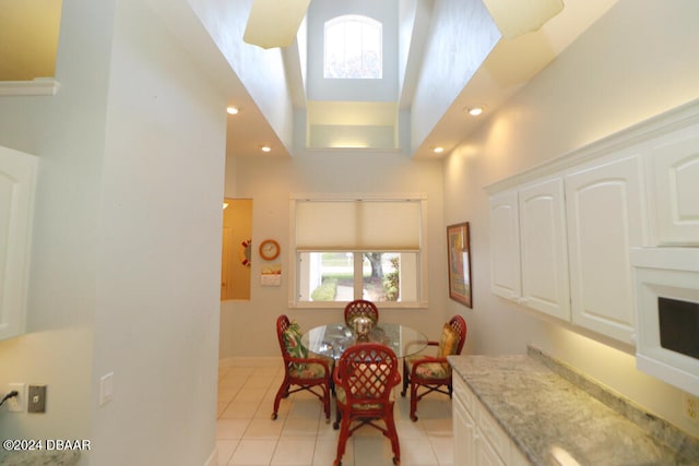 tiled dining room with a towering ceiling, a healthy amount of sunlight, and a skylight