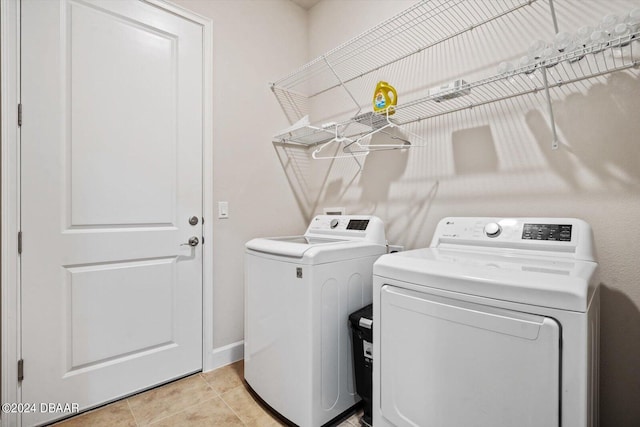 laundry area with separate washer and dryer and light tile patterned flooring