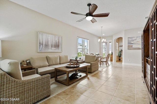 tiled living room with ceiling fan with notable chandelier