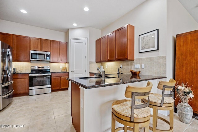 kitchen featuring stainless steel appliances, a kitchen breakfast bar, sink, and kitchen peninsula