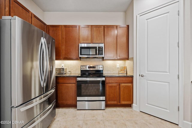 kitchen with stainless steel appliances, dark stone counters, and backsplash