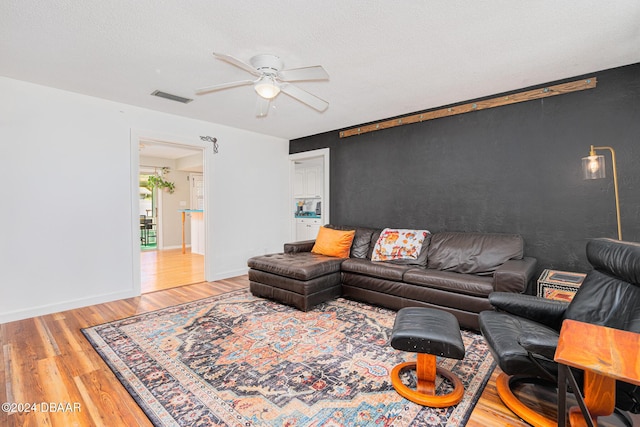 living room with ceiling fan, hardwood / wood-style floors, and a textured ceiling