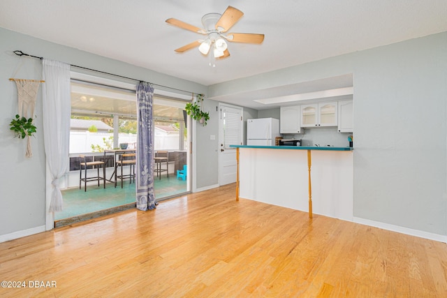 kitchen featuring ceiling fan, white refrigerator, kitchen peninsula, light hardwood / wood-style floors, and white cabinets