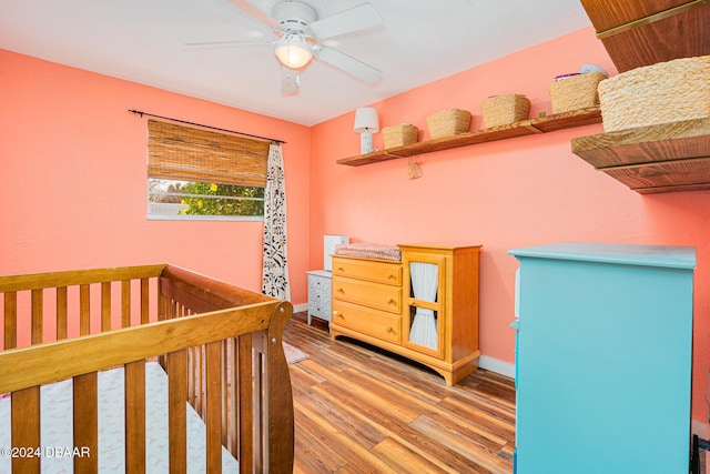 unfurnished bedroom featuring hardwood / wood-style flooring, ceiling fan, and a nursery area