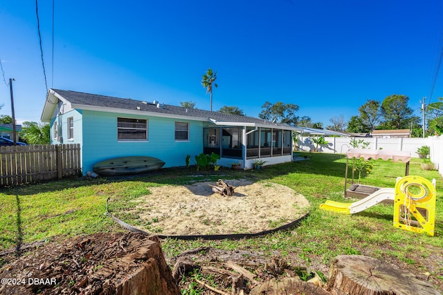 back of property featuring a playground, a sunroom, and a yard