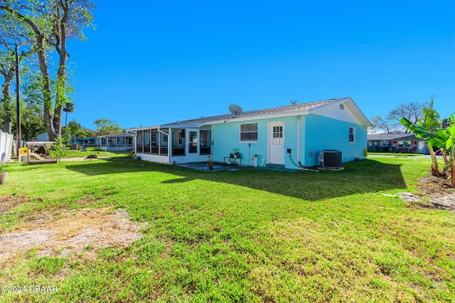 back of house with a lawn, a sunroom, and central AC unit