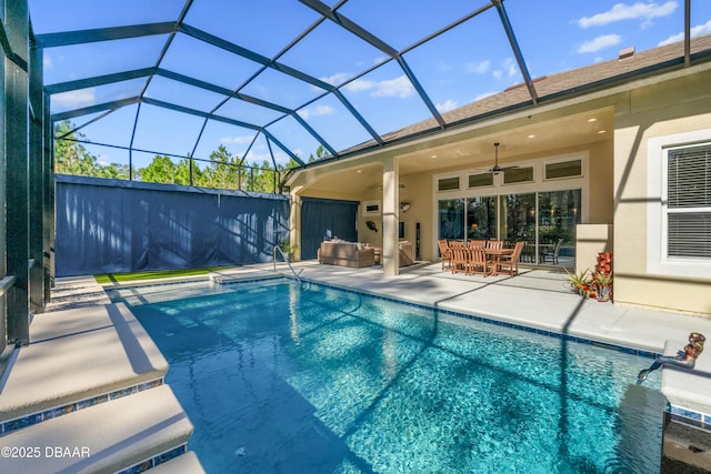 view of pool featuring an outdoor hangout area, a patio area, ceiling fan, and glass enclosure