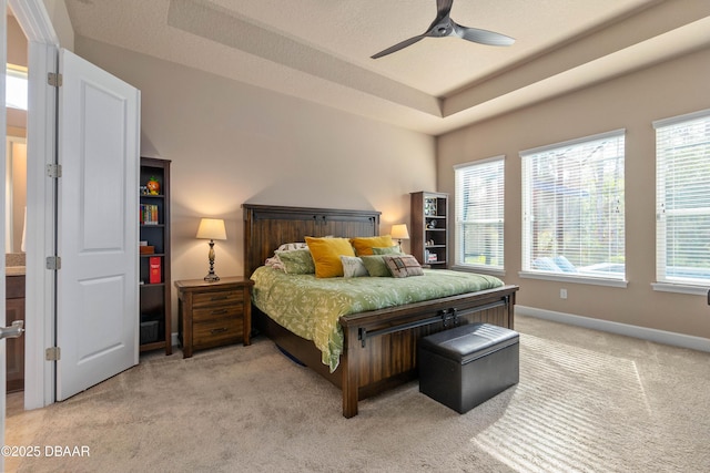 carpeted bedroom featuring ceiling fan and a raised ceiling